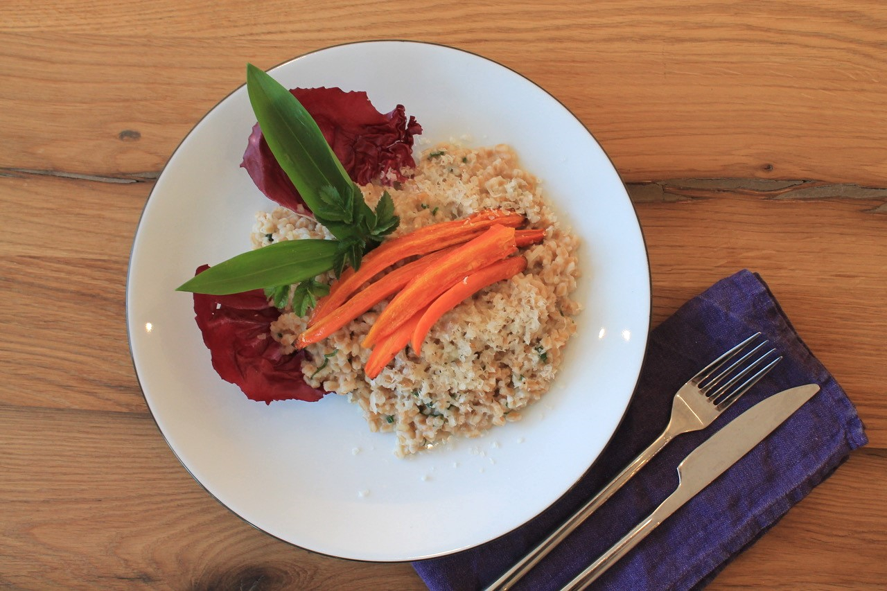 Ein Teller mit Emmer-Risotto mit Bärlauch und Ofenkarotten