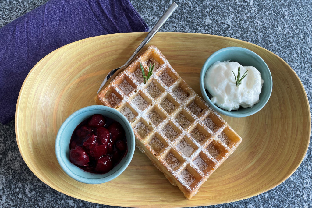 Frische Waffeln mit Puderzucker, Sahne und Kirschkompott